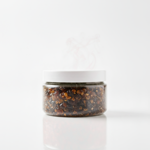 Pot d'encens Oud Hajarah, résine sombre et parfumée, produit naturel d'Oman présenté dans un contenant en verre élégant.