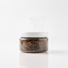 Pot d'encens Oud Hajarah, résine sombre et parfumée, produit naturel d'Oman présenté dans un contenant en verre élégant.